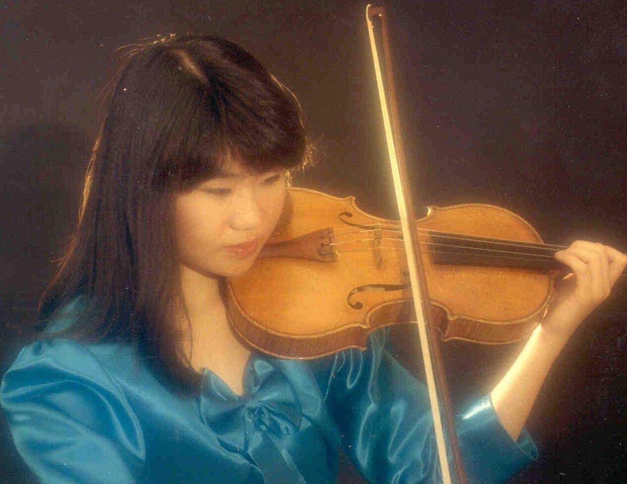 A woman with sholder-length, black hair plays the viola.