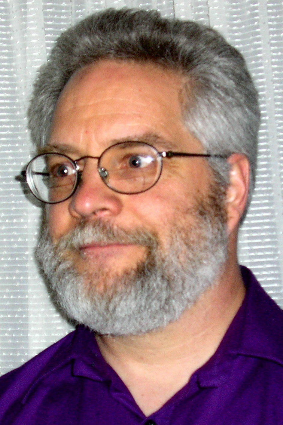 A headshot of a bespectacled man with gray hair and a gray beard.